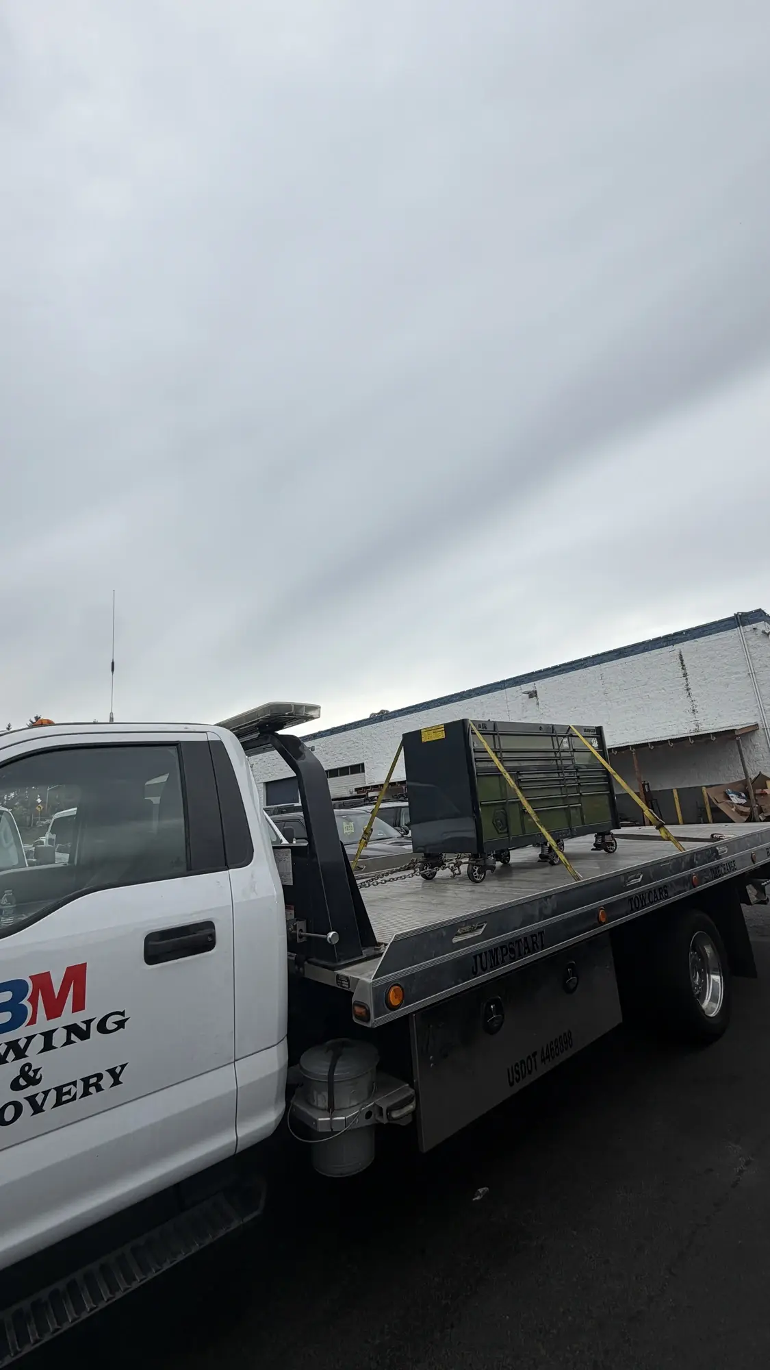 BM Towing flatbed hauling a large tool cabinet strapped down